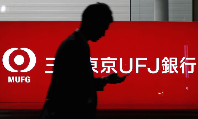 A pedestrian walks past signage for Bank of Tokyo Mitsubishi UFJ Ltd. at a branch in Tokyo, Japan. Photographer: Kiyoshi Ota/Bloomberg